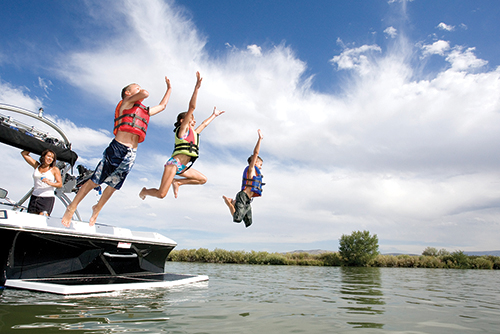 kids jumping into water from boat
