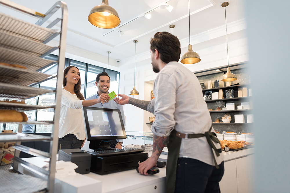 Happy couple shopping with debit card in bakery