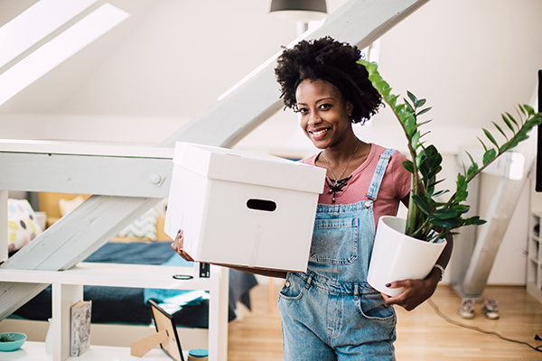 woman holding moving box and house plant