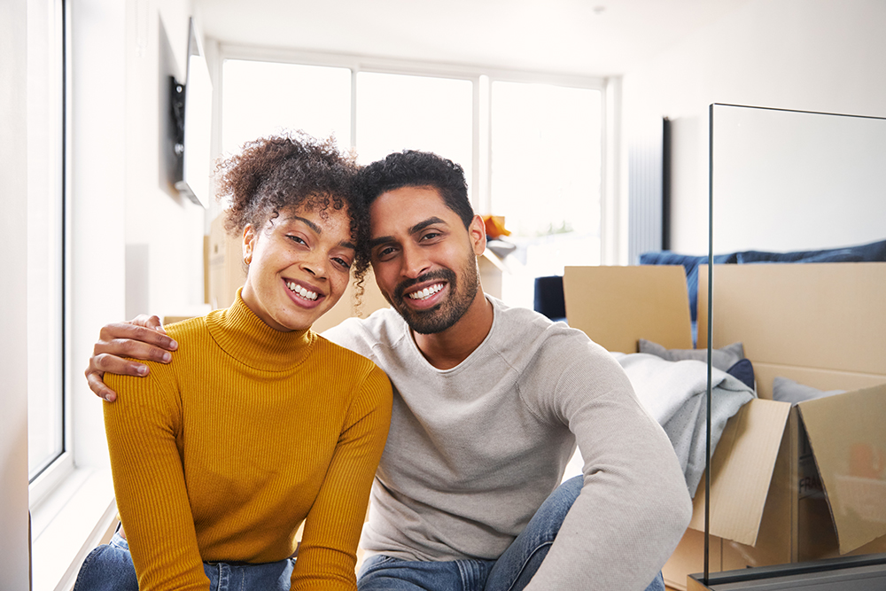 happy couple sitting on the floor with moving boxes