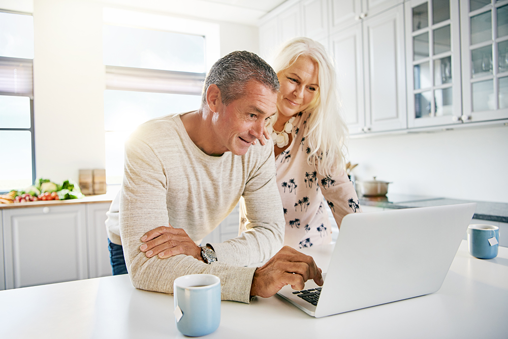 couple using laptop at kitchen counter