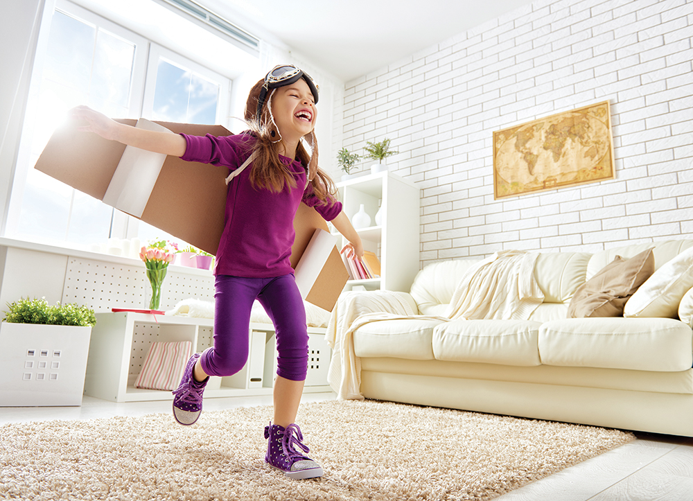 Happy young girl playing with cardboard wings