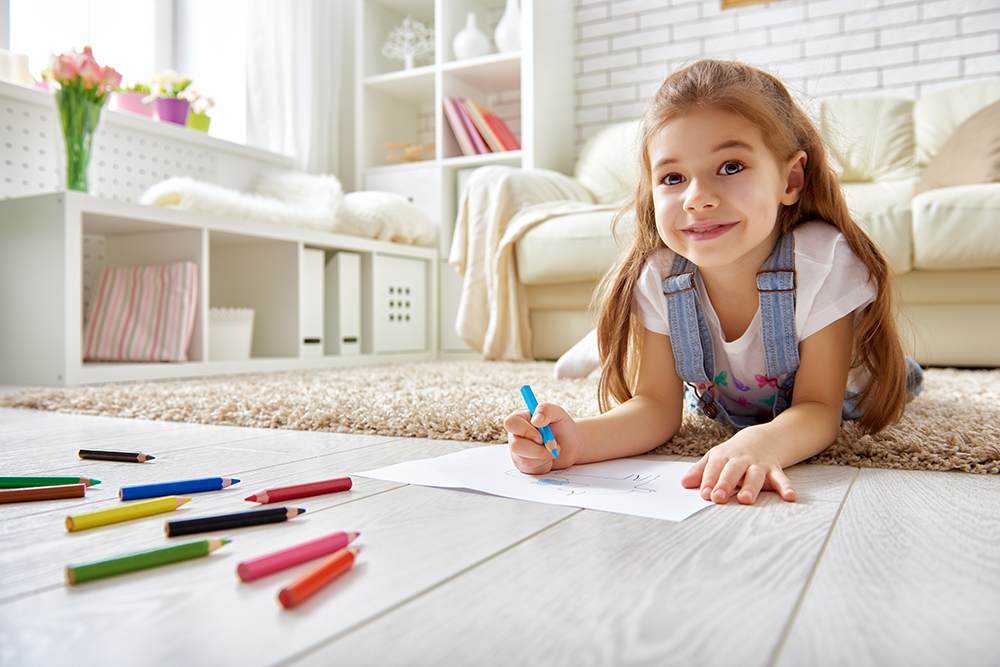 Happy young girl coloring with pencils