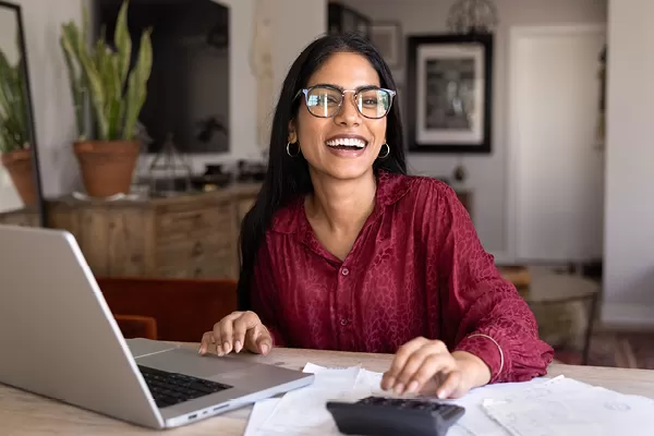 Girl smiling at her computer and desk with a calculator