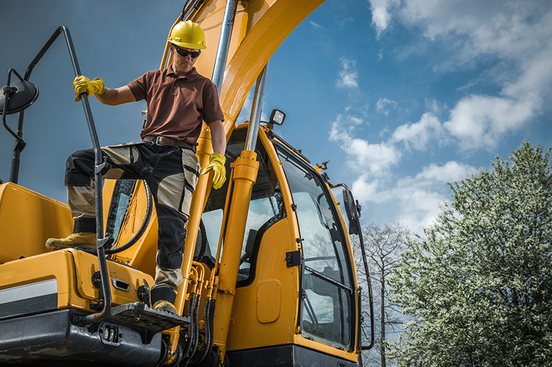 man climbing down the steps of large industrial machine