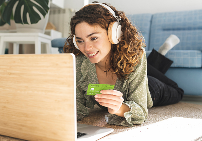 Woman looking at a laptop holding a debit card