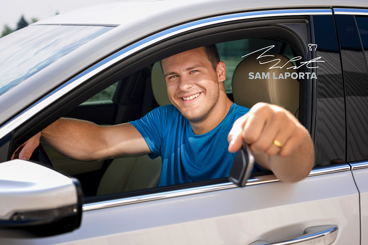 Sam LaPorta sitting in drivers seat of car holding keys out the window and smiling