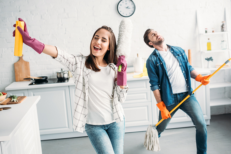 Couple dancing in kitchen and cleaning