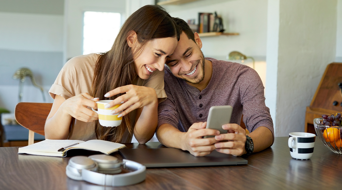 Couple sitting at a table together looking at a phone