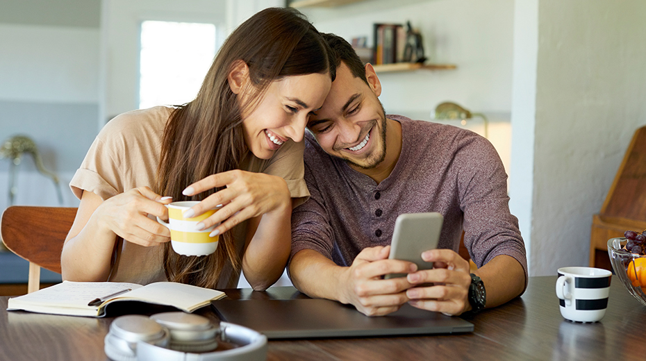 Couple sitting at a table together looking at a phone