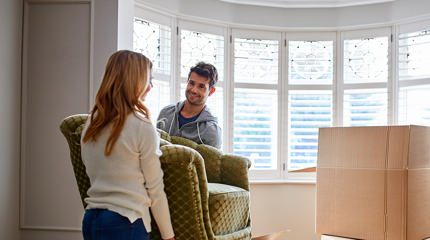 Couple moving furniture into new home
