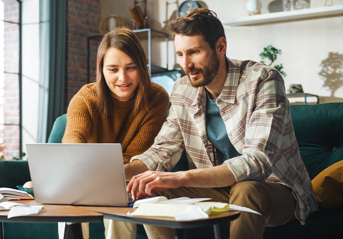 a couple sitting at a table with a laptop and documents